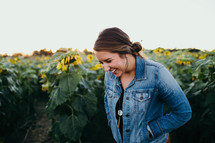 a woman laughing standing in a field of sunflowers 