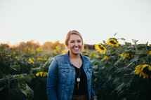 smiling young woman standing in a field of sunflowers 