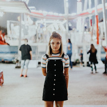 a teen girl standing in front of a ferris wheel 