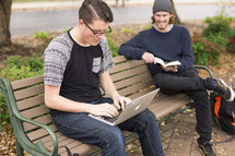 college students sitting on a bench on campus studying 