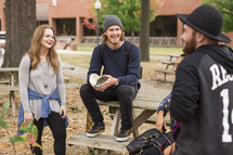 students gathered sitting around picnic table on campus 