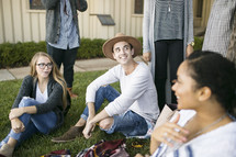 friends sitting on blankets in the grass talking 