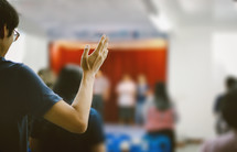 a person standing with hands raised at a worship service 