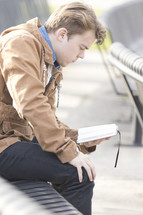 a man reading a Bible sitting on a bench 