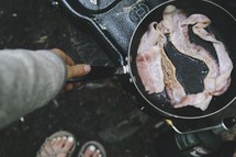 campers cooking bacon on a propane stove 