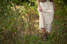 boots of a woman walking in tall grass and dense vegetation 