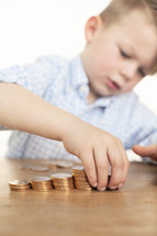 a boy child stacking gold coins 