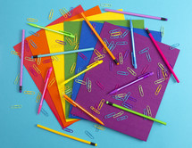 rainbow colored paperclips, pencils, and paper 