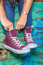 teen girl adjusting her converse sneakers 