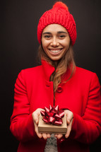 a woman in a red trench coat holding a gift box at Christmas 