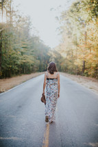 young woman walking down the center of a road 