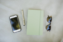 iPhone, pen, journal, and sunglasses 
