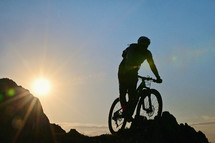 Silhouette Of A Cyclist Standing on Clif Against The Sun in Spring Time