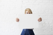 woman holding up a blank piece of paper 
