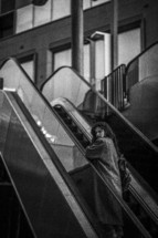 a woman in a trench coat on an escalator 