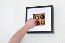 Man's Hand Picking Up Chocolate Pralines in Photo Frame