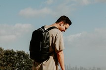 young man with a book bag and distant city view