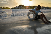 man sitting on a beach with a life preserver ring 