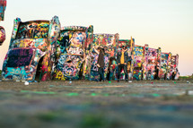 people standing in front of graffiti covered cars 