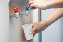 Man filling plastic cup at water cooler