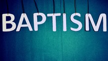 Letters spelling the word, "baptism," suspended from string.