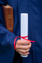 graduate holding a diploma and Bible 