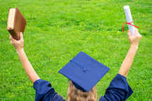graduate holding a diploma and Bible up in the air 