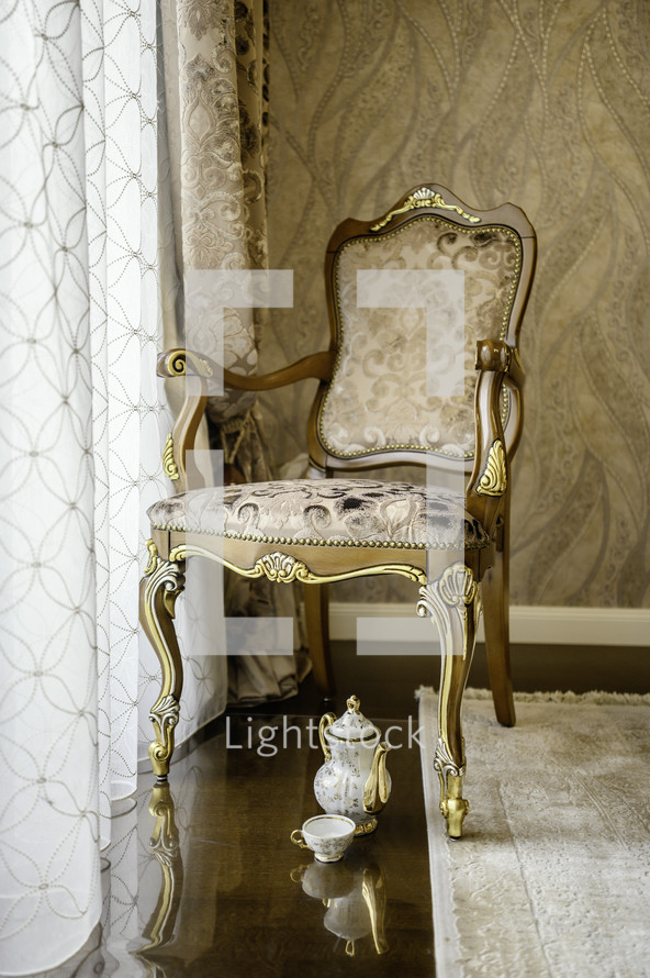 Ornate gold chair and tea pot on floor