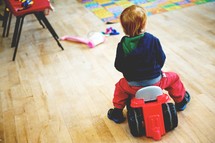 Young boy in a play room riding on a wheeled toy