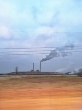 smoke from a distant factory across a field 
