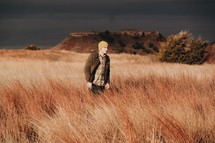 man walking in tall brown grasses 