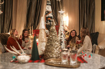 Christmas tree decorations on a table and women gathered in a living room 