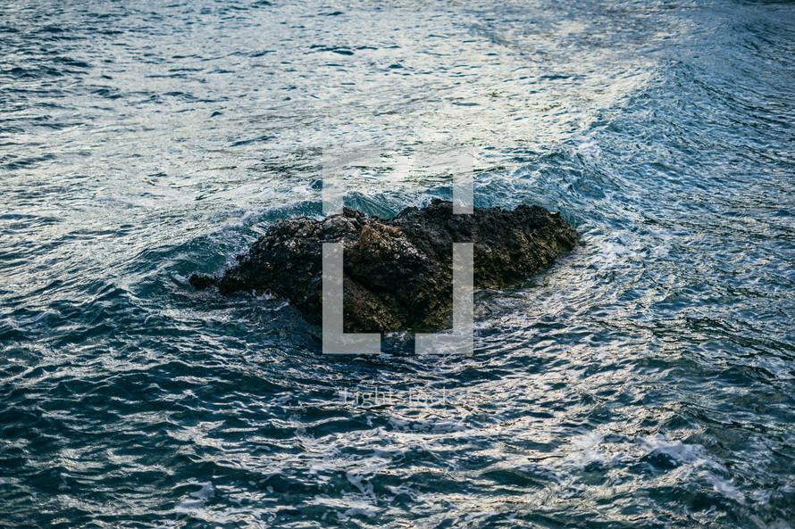 aerial view over a rock in the ocean 