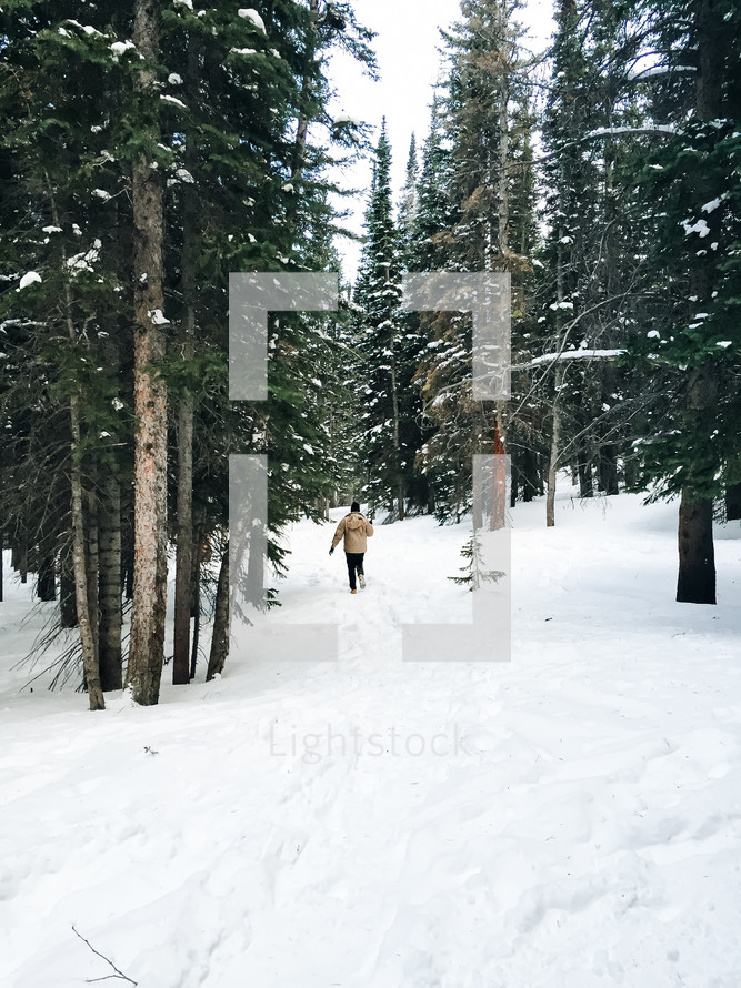 man walking through deep snow in a forest 