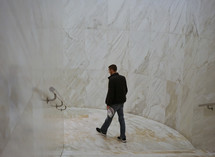 a man walking through a marble hallway 