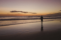 A man walks on a beach beside the ocean.