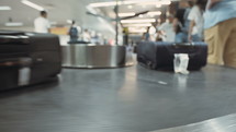 Passengers collecting luggage from a conveyor belt at the airport.