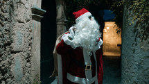 Santa walking down a narrow street on Christmas night 
