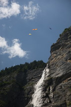 Birds flying over a waterfall on a mountainside.
