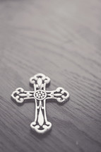 Silver cross on a wood table.
