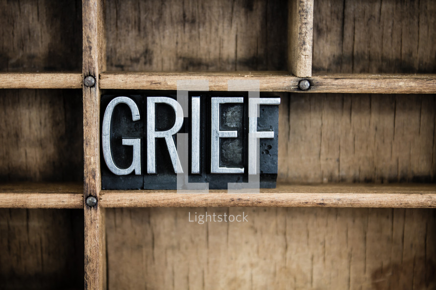 word grief in blocks on a bookshelf 
