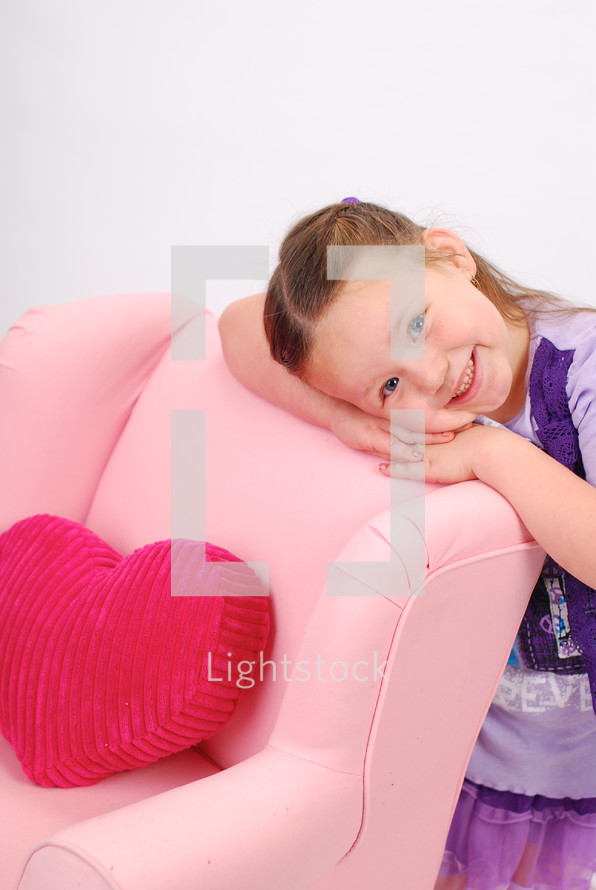 girl child resting her head on a pink recliner 