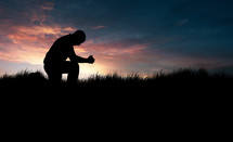 silhouette of a man in prayer at sunset