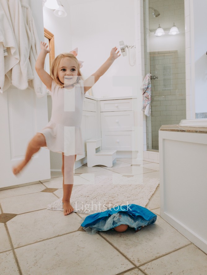 toddler girl dancing in the bathroom as mom gets ready 