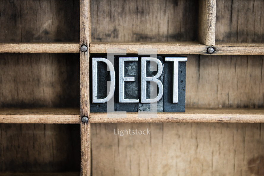 word debt in blocks on a shelf 