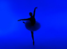 Beautiful silhouette of ballerina on blue background dancing ballet. Woman performs smooth movements. Sensual dancer in tutu dress on scene under neon light.