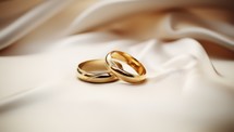 Wedding rings on white satin cloth, closeup view