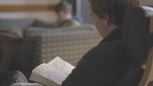 Over the shoulder view of a man reading his Bible in a small group Bible study.