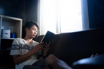 Asian man holding a Bible and reading
