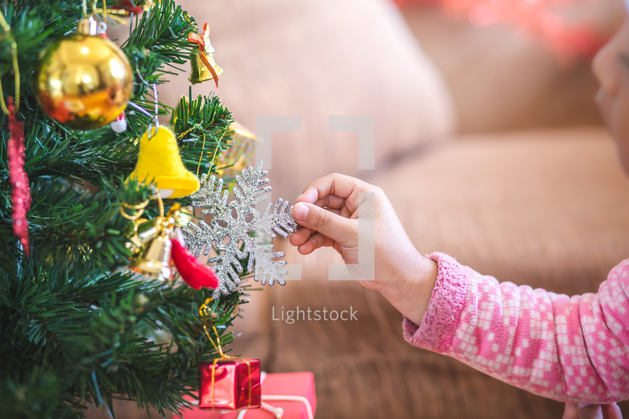 a toddler girl decorating a Christmas tree 
